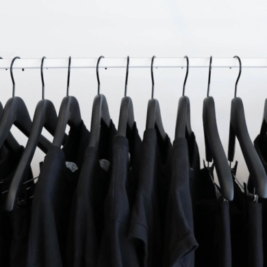 dark dresses on black hangers on a white closet rod