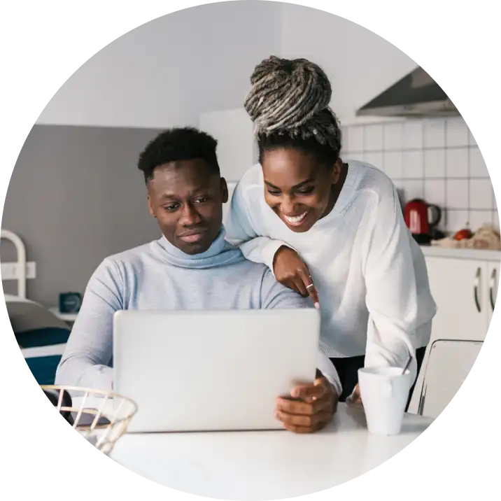 Two people sit at a laptop discussing their housing options