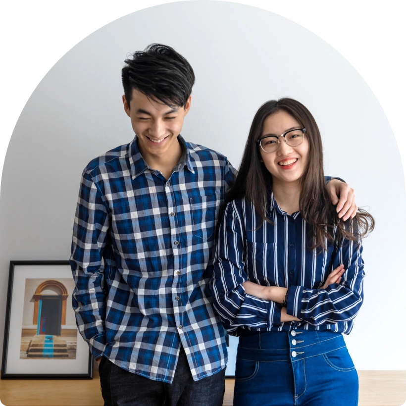 Two people in a well-lit room with plaid and stripped blue shirts smiling at the camera