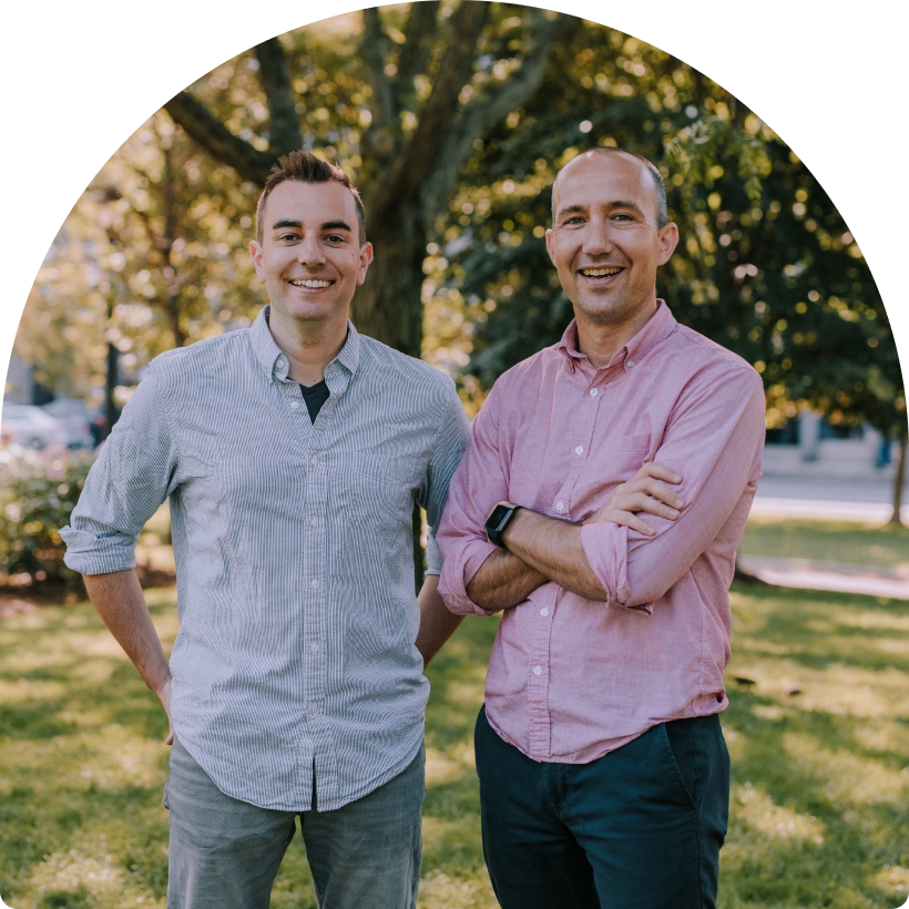 Own Up Co-founders Patrick and Mike stand side by side in a park and smile at the camera