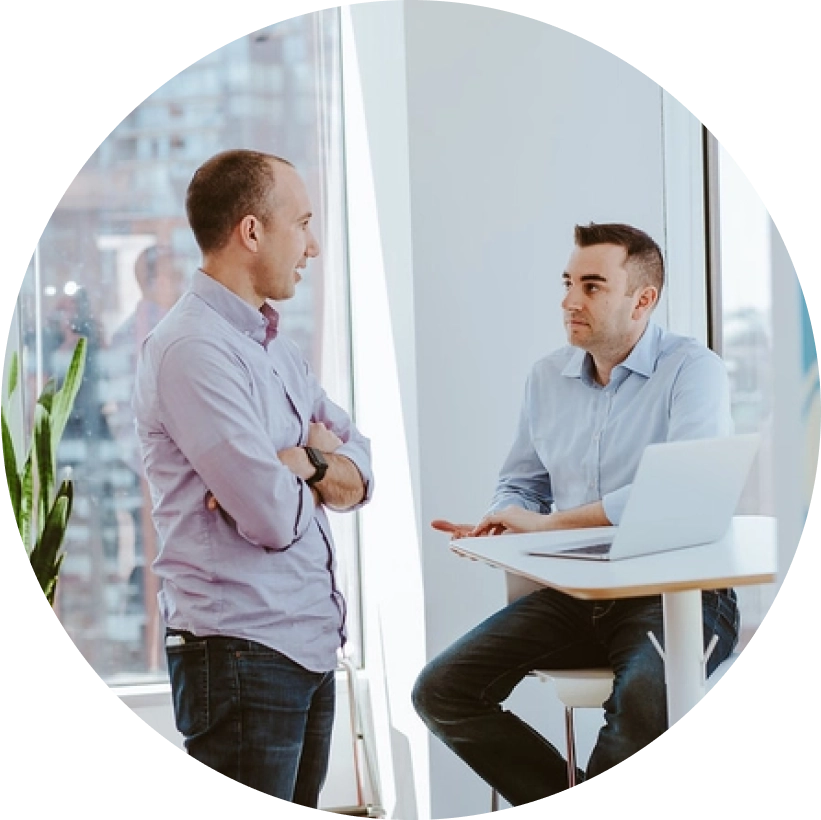 Own Up Co-founders Patrick and Mike chat at a hightop table in a bright room filled with sunlight